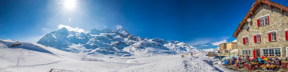 Skiers eat lunch and look out over perfect sun-drenched snow-filled slopes